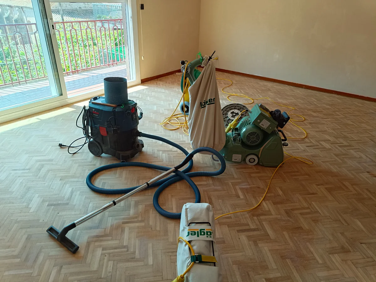 Lijado de parquet con lijadora y aspirador en una vivienda