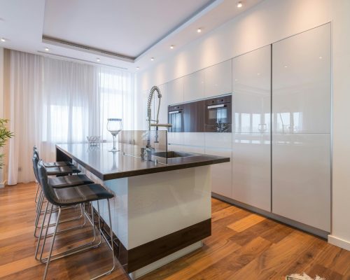 Cocina abierta con isla y suelo de aspecto madera en tono nogal